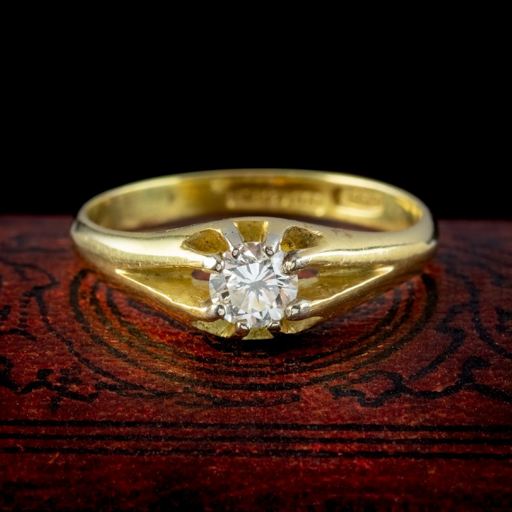 An antique Edwardian yellow gold solitaire ring set with a single round diamond held in a carved claw setting.