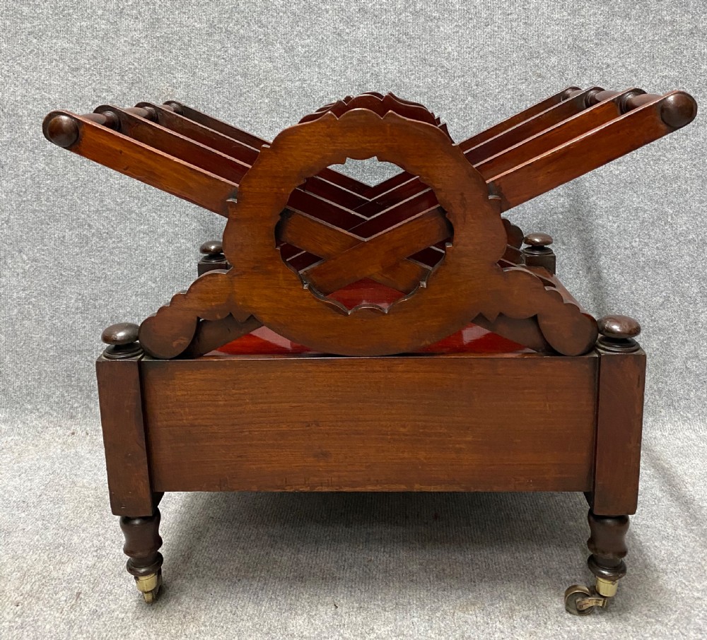 An antique mahogany music canterbury featuring carved acanthus side rails, slatted dividers, a single lower drawer with a central knob handle, and turned legs set on brass castors. View VIII