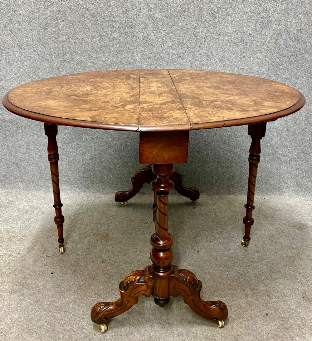 A Victorian burr walnut drop-leaf table featuring symmetrical figured grain, turned supports, spiral stretchers, and carved legs on castors. View IV
