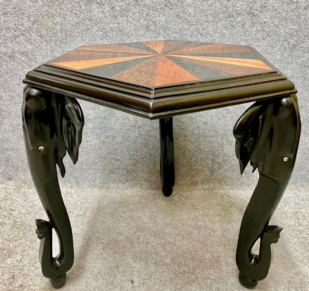 An hexagonal antique side table featuring a radiating starburst specimen wood top supported by hand-carved ebony elephant legs. View II
