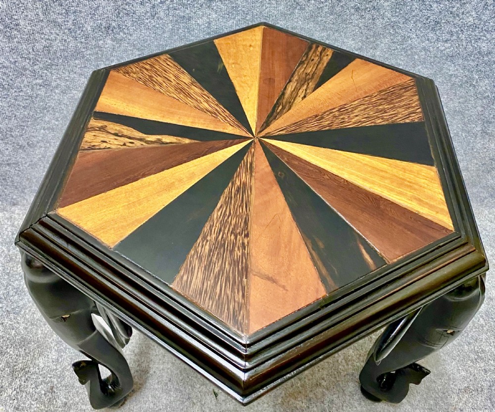 An hexagonal antique side table featuring a radiating starburst specimen wood top supported by hand-carved ebony elephant legs. View III