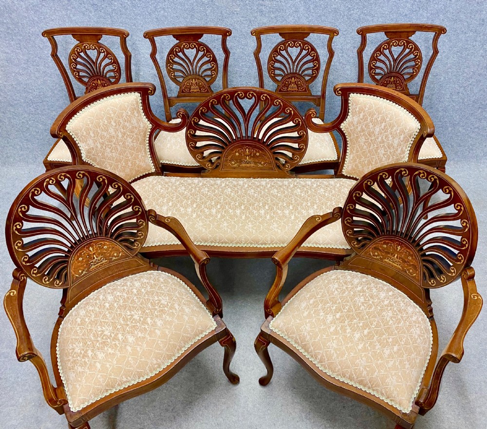An Edwardian parlour suite featuring a mahogany settee, armchairs, and side chairs with pierced fan-backrests and cream patterned upholstered seats.