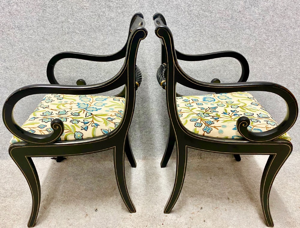 A pair of black ebonised Regency style armchairs featuring gold gilt classical motifs on the top rails, swept scrolled arms, and botanical fabric seats. View III