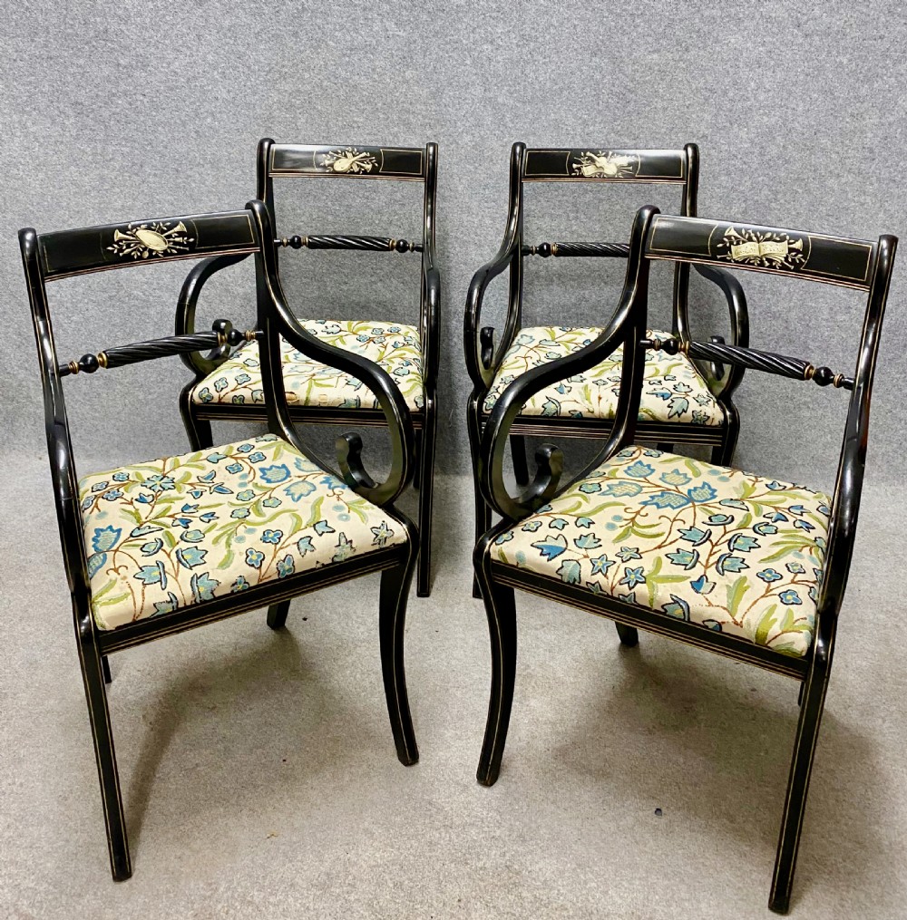 A set of four ebonised Regency style elbow chairs featuring sweeping armrests, hand-painted classical crest rails, and floral upholstered seats. View II
