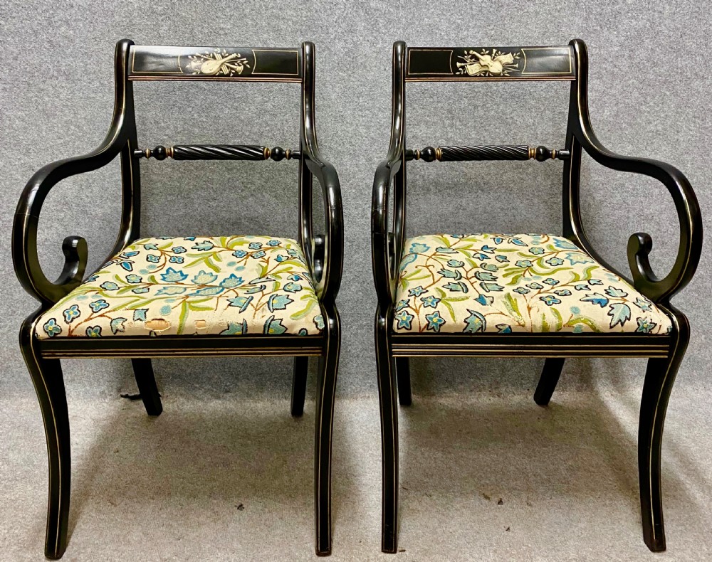 A set of four ebonised Regency style elbow chairs featuring sweeping armrests, hand-painted classical crest rails, and floral upholstered seats. View VIII
