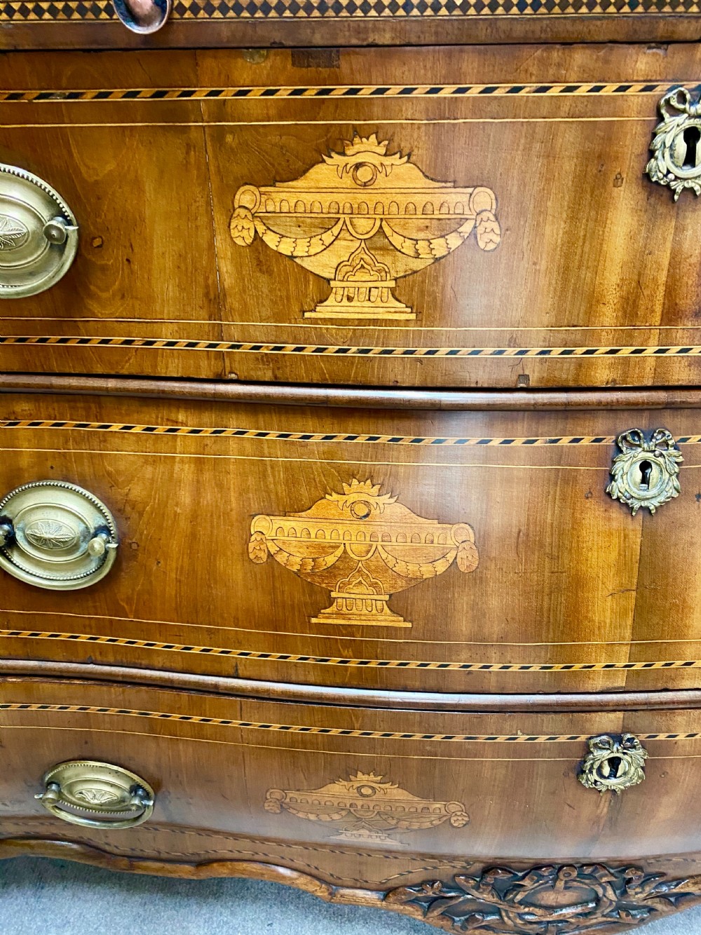 A Dutch marquetry cylinder bureau crafted from warm brown wood with trompe loeil writing tool inlays, fitted drawers, brass handles, and a curved bombe base. View VIII