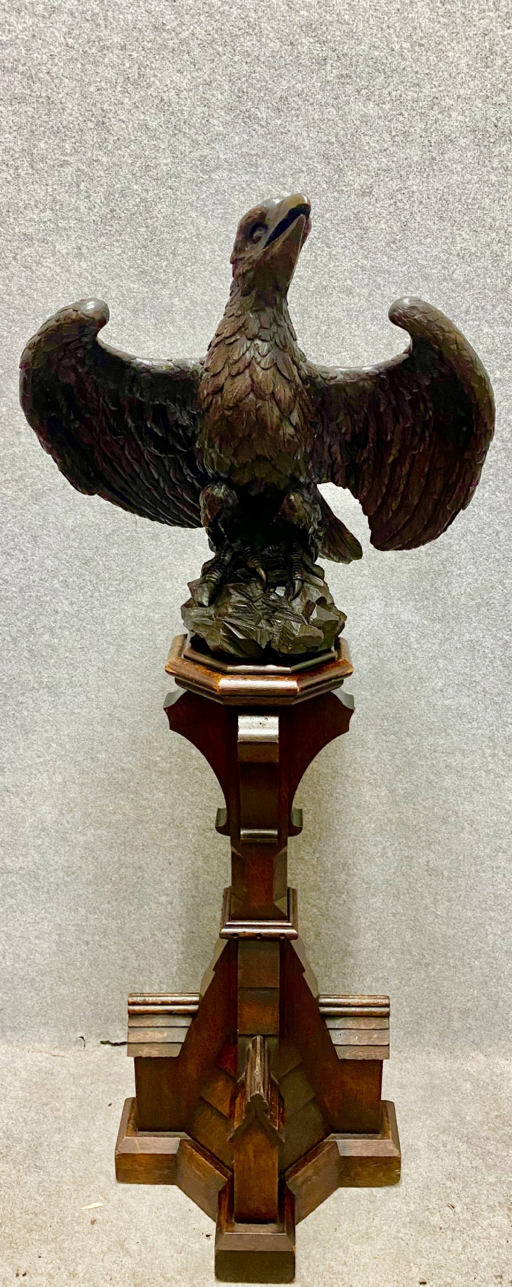 A dark carved oak eagle lectern featuring a sculpture of an eagle with wings spread mounted on an architectural pedestal stand.