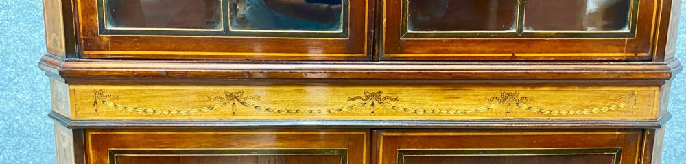 A tall mahogany and satinwood inlaid corner cabinet featuring a broken swan-neck pediment, upper astragal glazed double doors, and lower panelled cupboard doors. View VIII