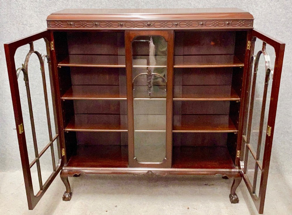 An Edwardian dark mahogany bookcase featuring three glazed doors with astragal tracery, elevated on carved cabriole legs with claw and ball feet. View IV