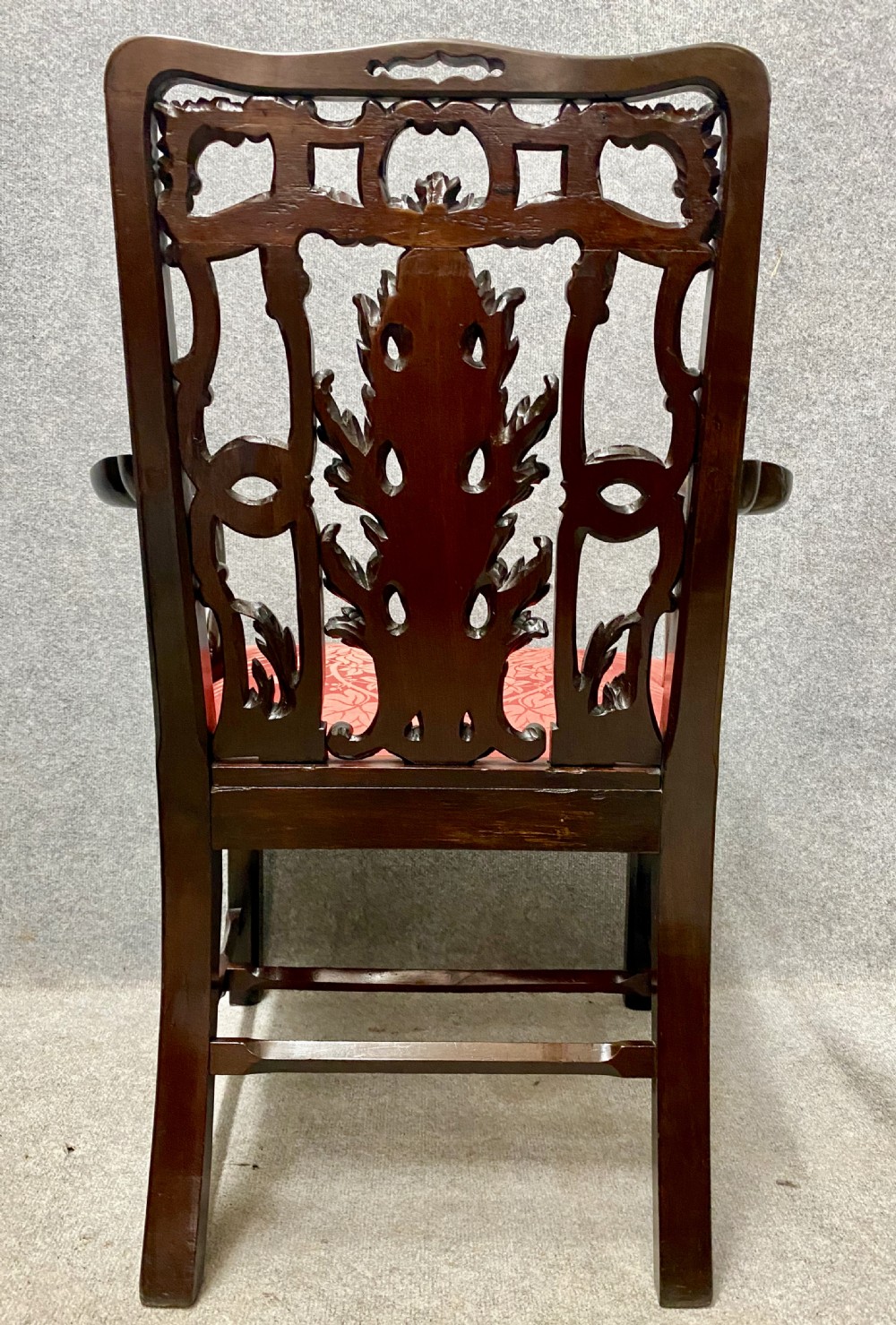 An 18th-century Georgian mahogany elbow chair featuring a detailed pierced splat back, blind fretwork on the front legs, and red patterned damask upholstery. View II