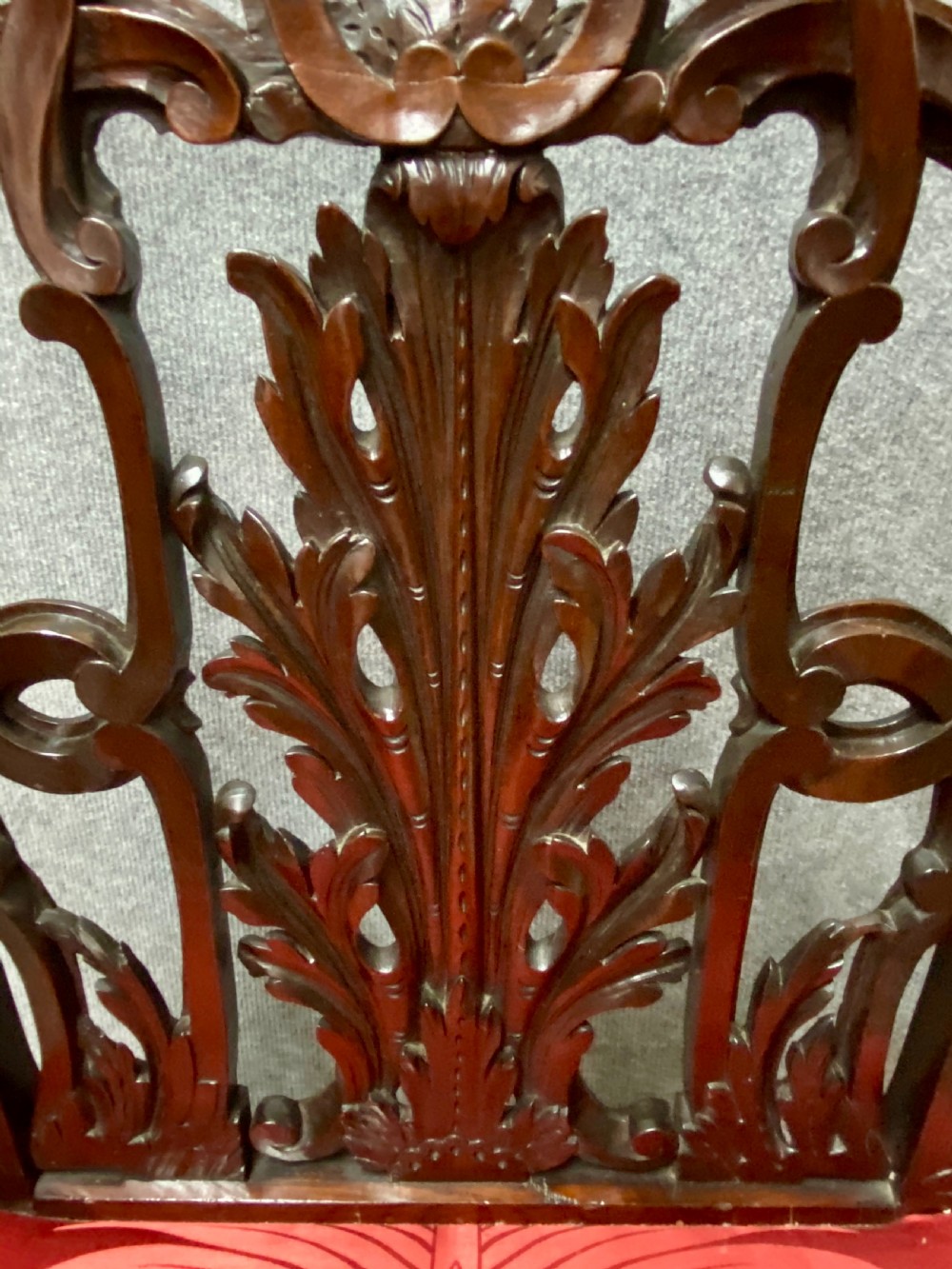 An 18th-century Georgian mahogany elbow chair featuring a detailed pierced splat back, blind fretwork on the front legs, and red patterned damask upholstery. View IV