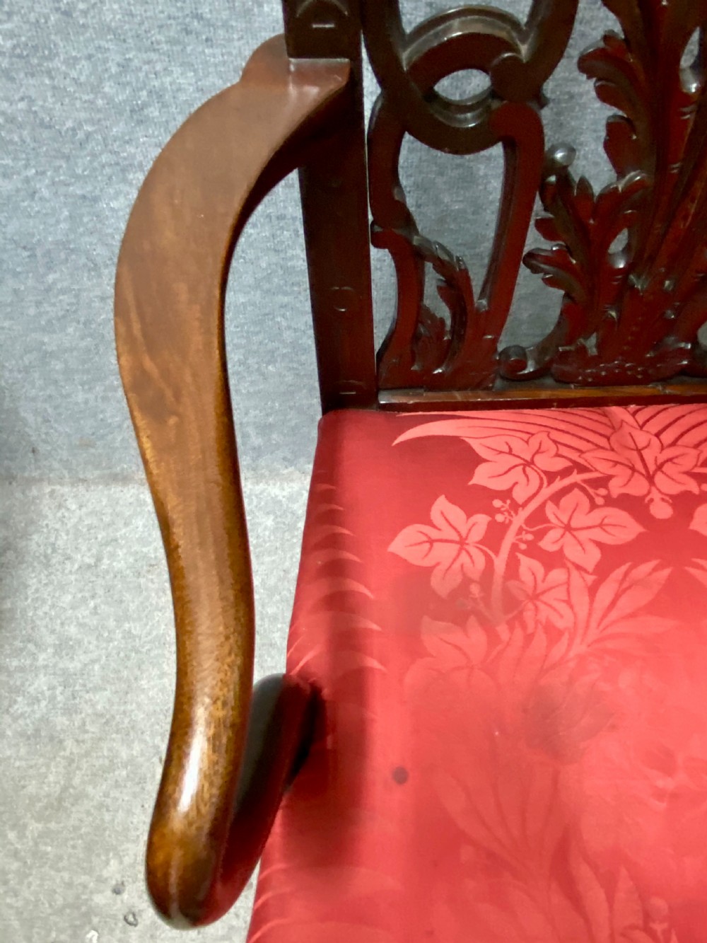 An 18th-century Georgian mahogany elbow chair featuring a detailed pierced splat back, blind fretwork on the front legs, and red patterned damask upholstery. View V