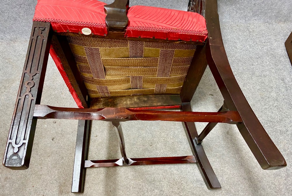 An 18th-century Georgian mahogany elbow chair featuring a detailed pierced splat back, blind fretwork on the front legs, and red patterned damask upholstery. View VII