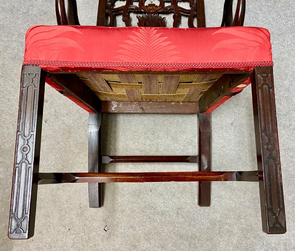 An 18th-century Georgian mahogany elbow chair featuring a detailed pierced splat back, blind fretwork on the front legs, and red patterned damask upholstery. View VIII