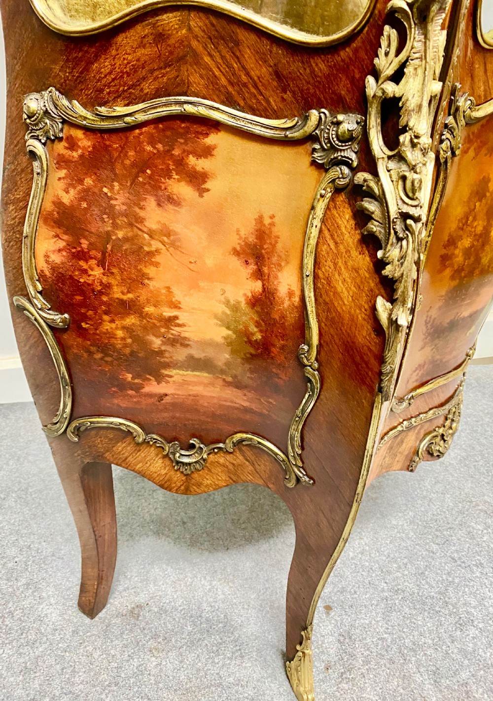 An antique French Louis XV style vitrine featuring serpentine glass sides, ornate gilt bronze mounts, and a lower painted Vernis Martin panel on cabriole legs. View VI