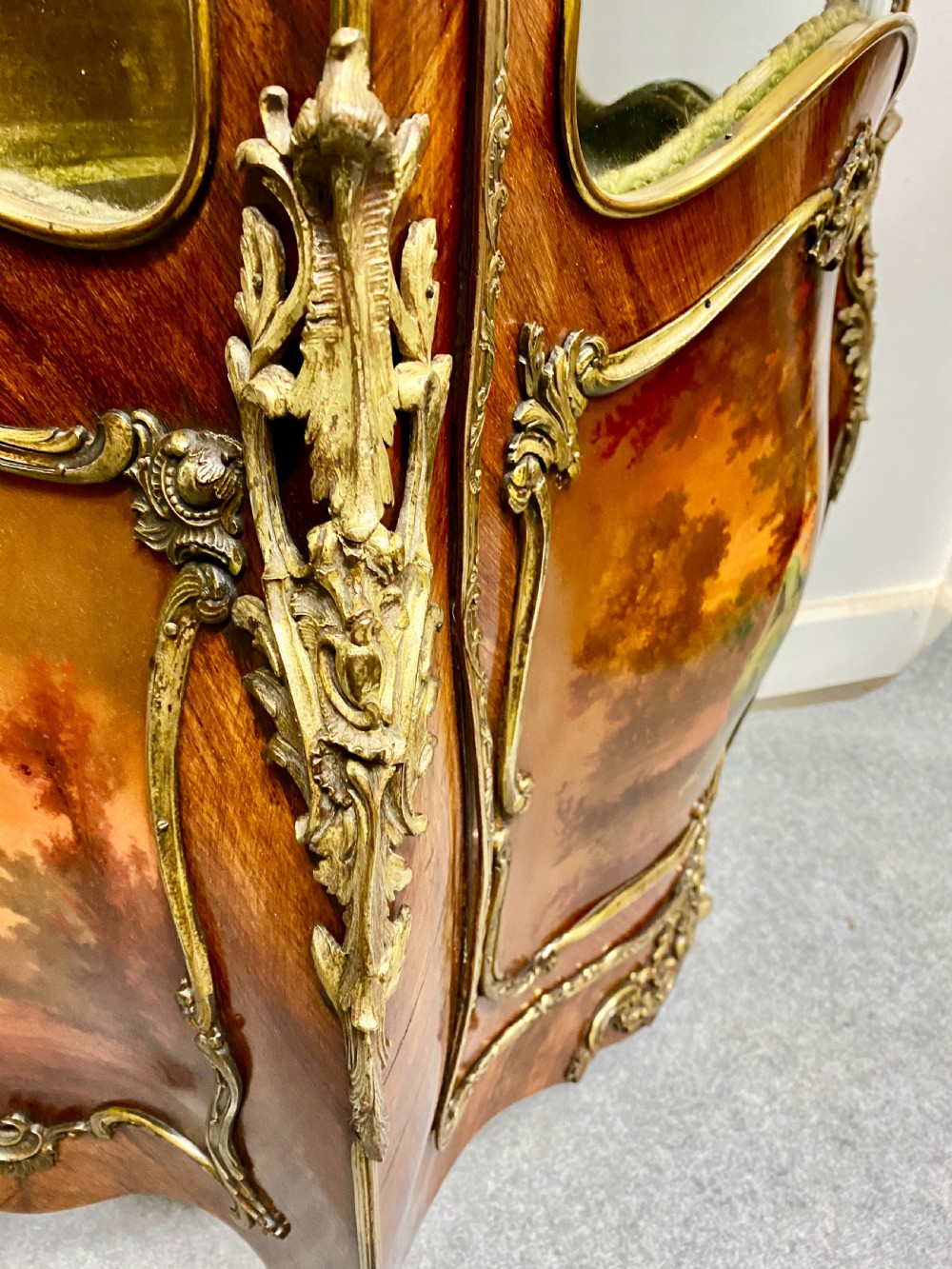 An antique French Louis XV style vitrine featuring serpentine glass sides, ornate gilt bronze mounts, and a lower painted Vernis Martin panel on cabriole legs. View VII