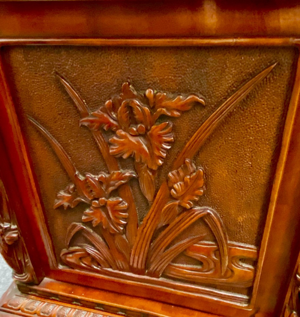 A reddish brown carved cinnabar lacquer cabinet with floral relief panels resting on a tall cabriole leg stand with an open side door. View VIII