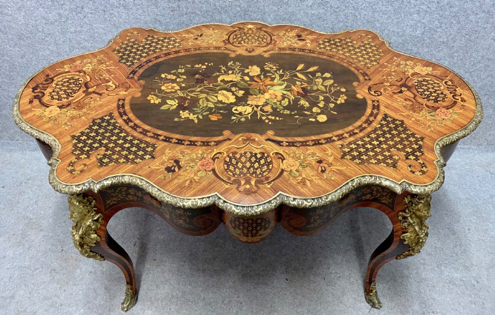 A French Louis XV style centre table featuring intricate floral marquetry inlay, a serpentine contoured top, cabriole legs, and bronze espagnolette mounts. View IX