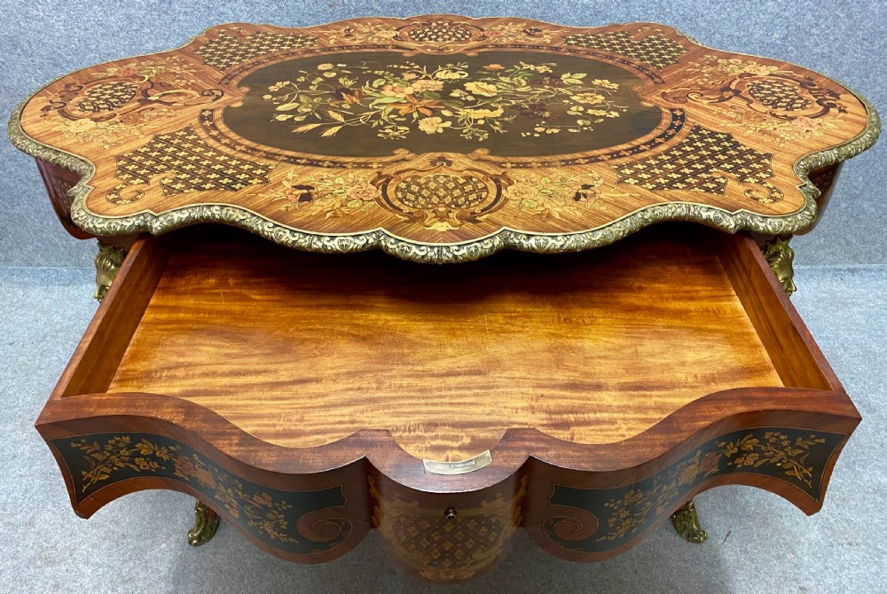 A French Louis XV style centre table featuring intricate floral marquetry inlay, a serpentine contoured top, cabriole legs, and bronze espagnolette mounts. View II