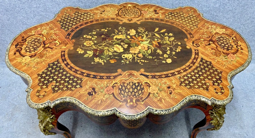 A French Louis XV style centre table featuring intricate floral marquetry inlay, a serpentine contoured top, cabriole legs, and bronze espagnolette mounts. View III