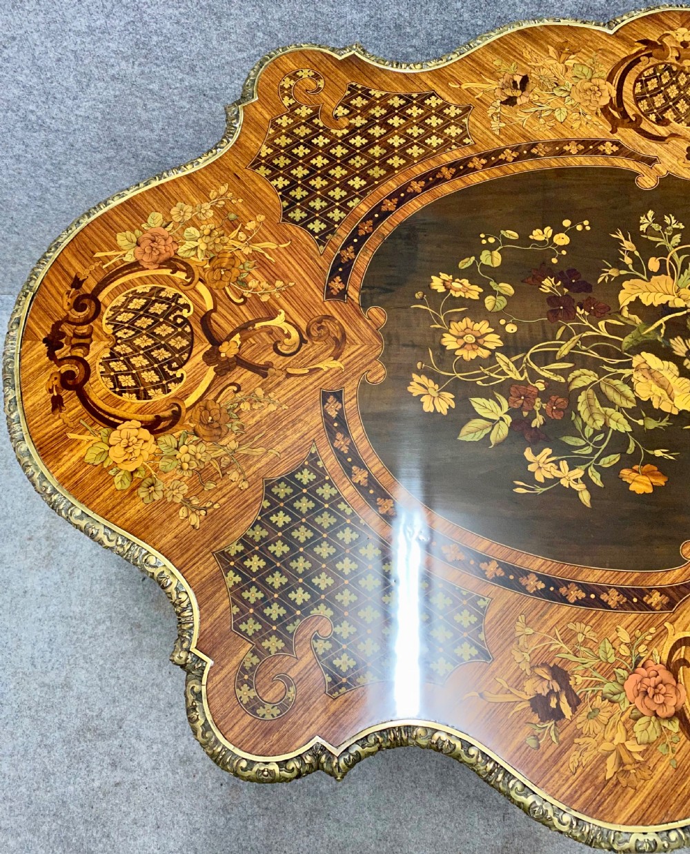 A French Louis XV style centre table featuring intricate floral marquetry inlay, a serpentine contoured top, cabriole legs, and bronze espagnolette mounts. View V
