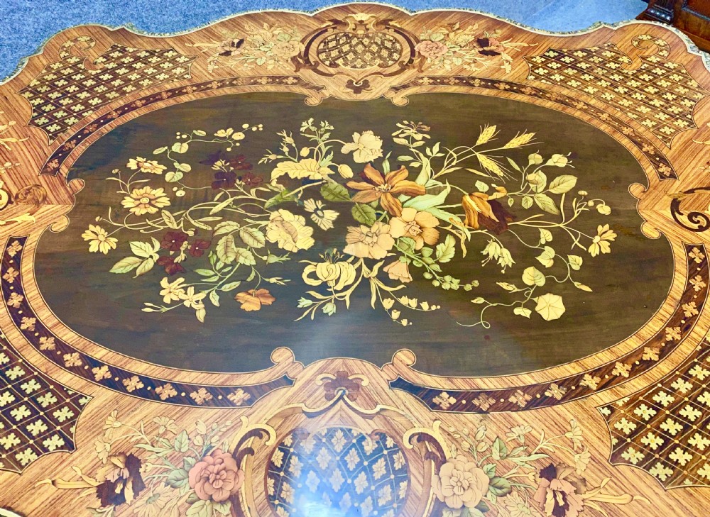 A French Louis XV style centre table featuring intricate floral marquetry inlay, a serpentine contoured top, cabriole legs, and bronze espagnolette mounts. View XV
