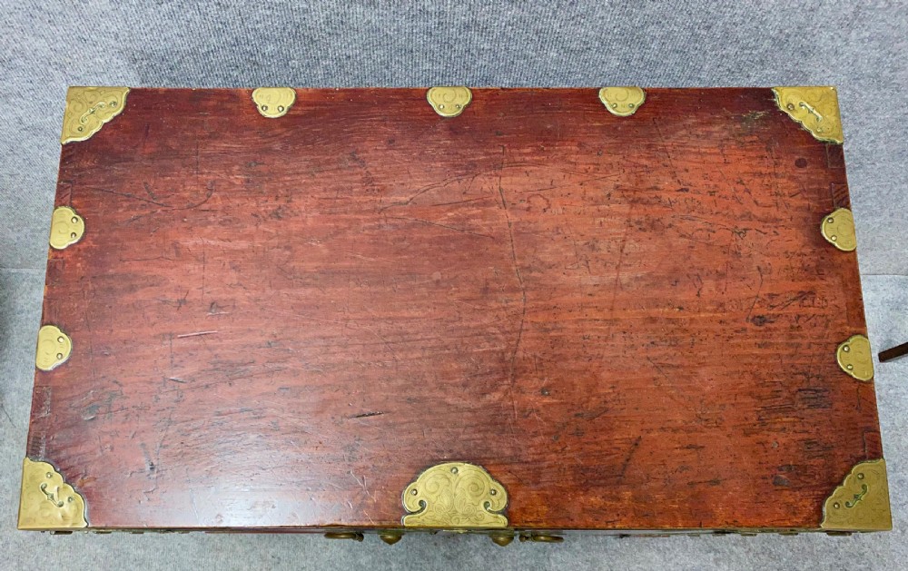 A small Chinese hardwood cabinet featuring polished dark wood, twin front doors, and decorative engraved brass mounts, hinges, and a central circular lockplate. View VII