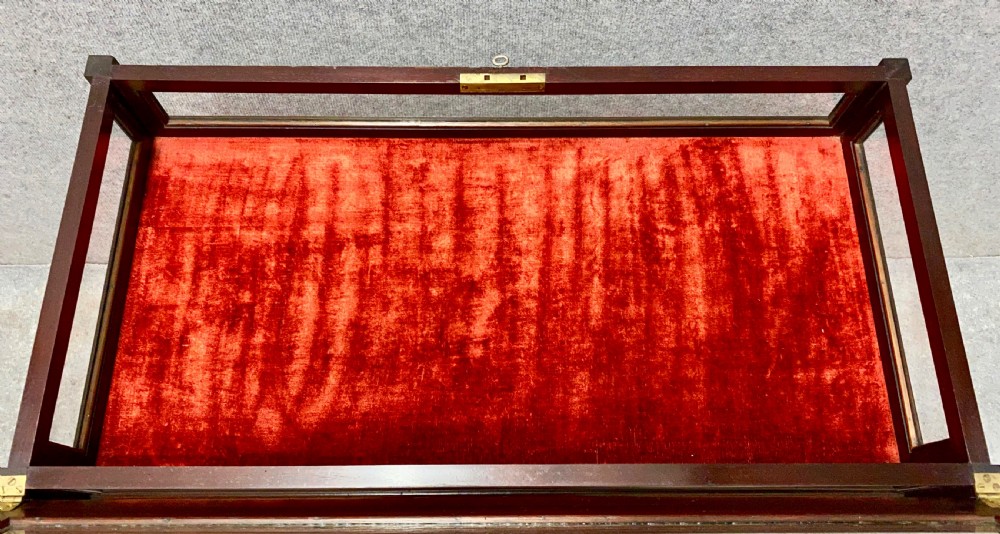 An antique glazed mahogany bijouterie table with a red fabric-lined display cavity, pierced fretwork corner brackets, and a lower shelf. View VI