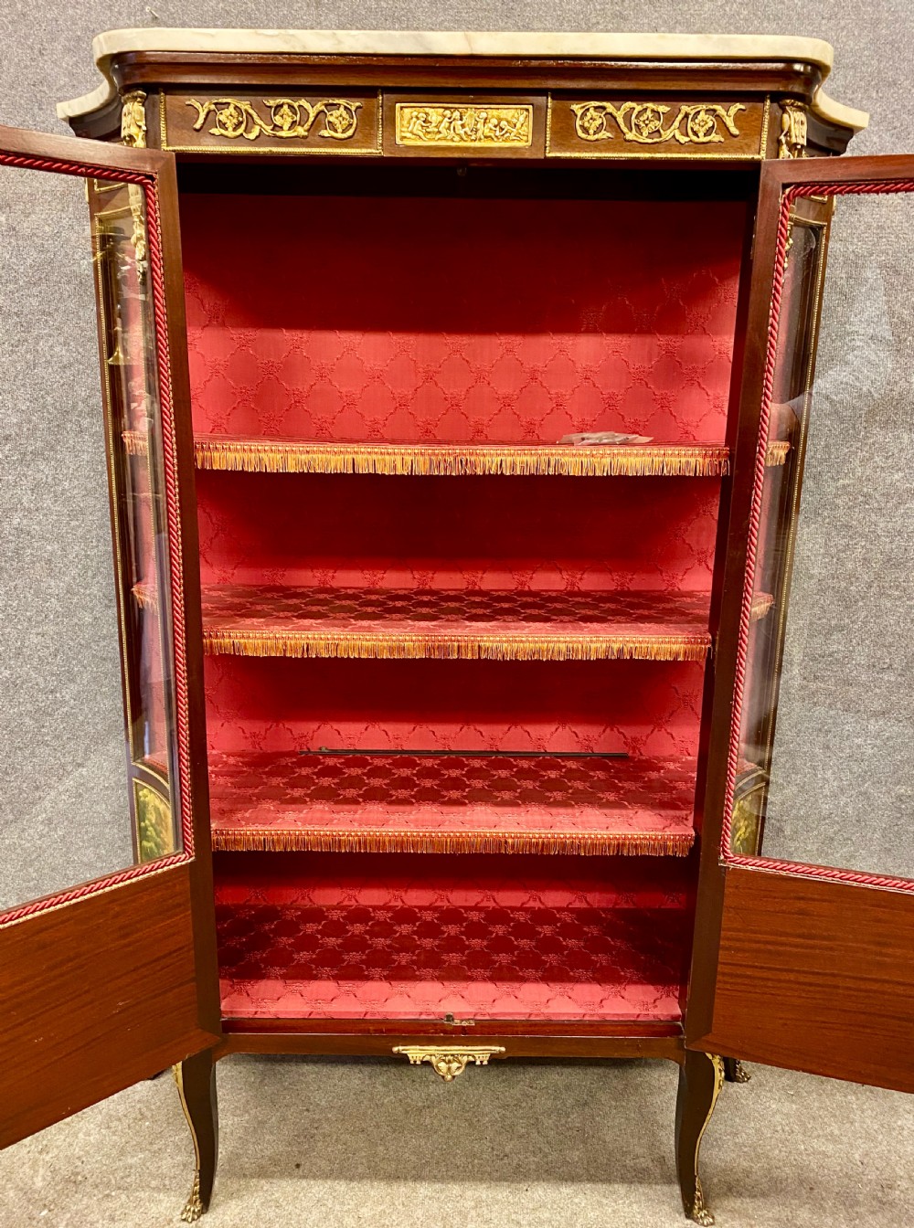 A French Louis XV style glazed display cabinet featuring serpentine glass side panels, a marble top, gilt bronze ormolu mounts, and hand-painted Vernis Martin panels at the base. View II