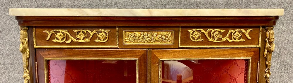 A French Louis XV style glazed display cabinet featuring serpentine glass side panels, a marble top, gilt bronze ormolu mounts, and hand-painted Vernis Martin panels at the base. View VII