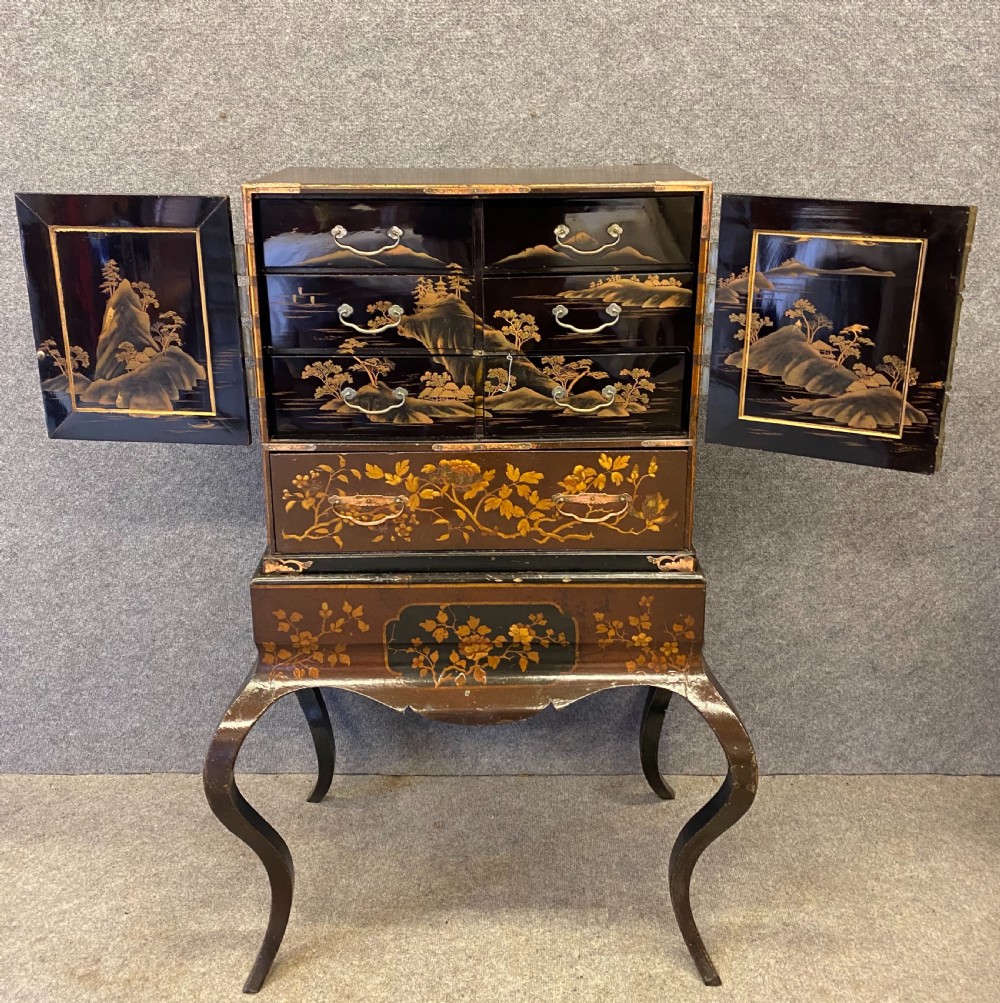 An antique Japanese Meiji period dark lacquer cabinet on a stand, decorated with gold floral and bird motifs and engraved metal mounts. View V