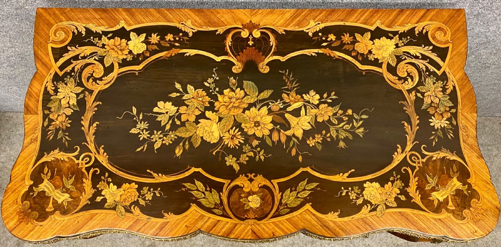 A Louis XV style serpentine card table featuring floral marquetry inlay, kingwood veneer, cabriole legs, and ornate gilt-bronze mounts. View V