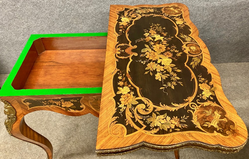 A Louis XV style serpentine card table featuring floral marquetry inlay, kingwood veneer, cabriole legs, and ornate gilt-bronze mounts. View X