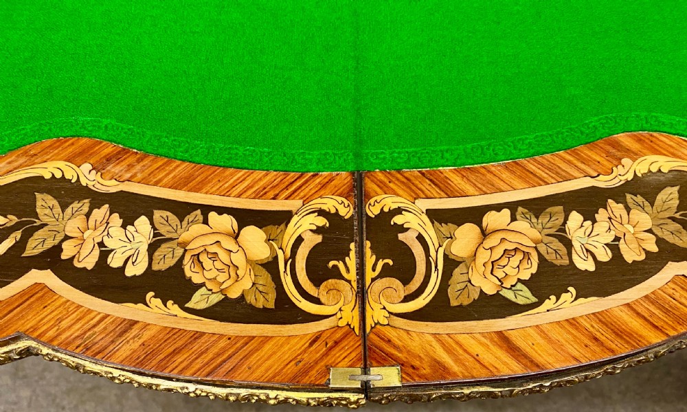 A Louis XV style serpentine card table featuring floral marquetry inlay, kingwood veneer, cabriole legs, and ornate gilt-bronze mounts. View XI
