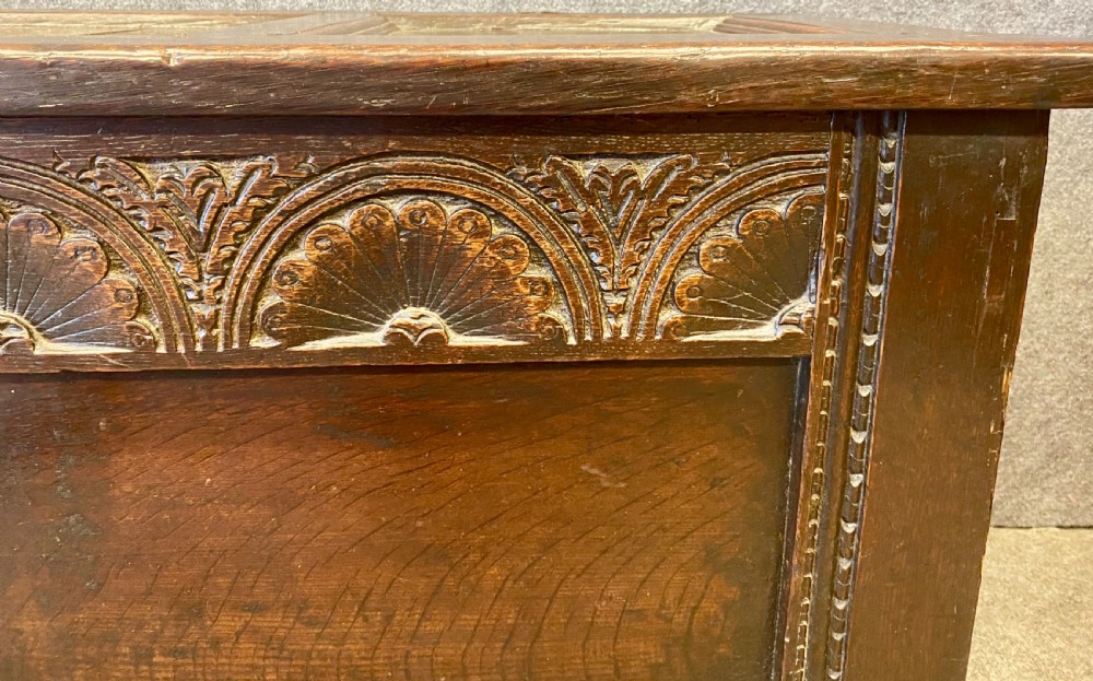 A small seventeenth-century style dark oak coffer featuring a carved lunette frieze, central rosette muntin, and an iron lock plate. View II