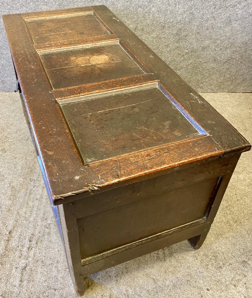 A small seventeenth-century style dark oak coffer featuring a carved lunette frieze, central rosette muntin, and an iron lock plate. View VI