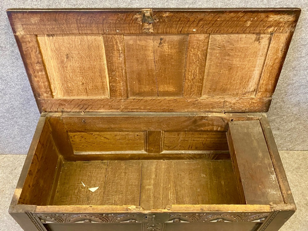 A small seventeenth-century style dark oak coffer featuring a carved lunette frieze, central rosette muntin, and an iron lock plate. View VII