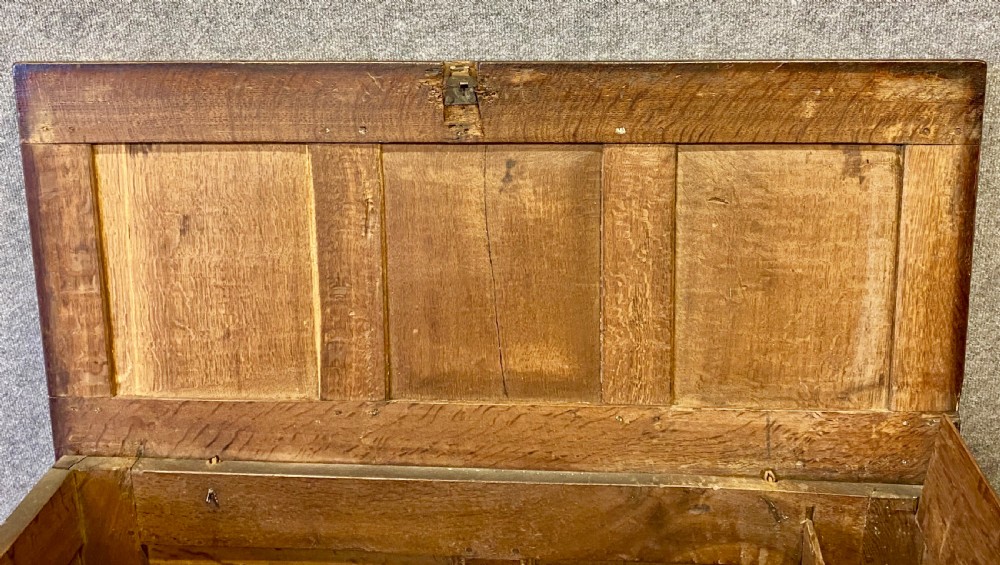 A small seventeenth-century style dark oak coffer featuring a carved lunette frieze, central rosette muntin, and an iron lock plate. View IX