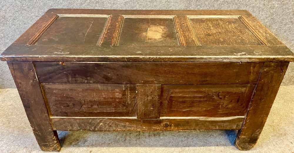 A small seventeenth-century style dark oak coffer featuring a carved lunette frieze, central rosette muntin, and an iron lock plate. View X