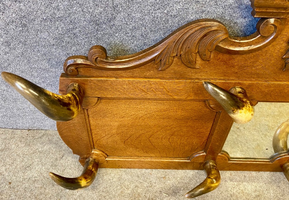 A nineteenth-century wall-mounted carved oak hall stand featuring eight horn hooks, a small central mirror, and scrollwork carving. View II