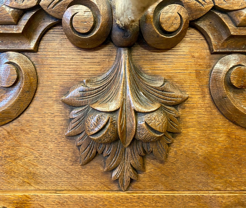 A nineteenth-century wall-mounted carved oak hall stand featuring eight horn hooks, a small central mirror, and scrollwork carving. View IV