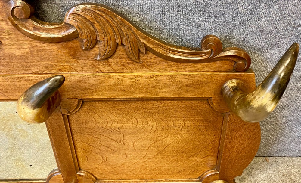 A nineteenth-century wall-mounted carved oak hall stand featuring eight horn hooks, a small central mirror, and scrollwork carving. View V
