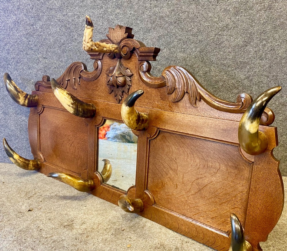 A nineteenth-century wall-mounted carved oak hall stand featuring eight horn hooks, a small central mirror, and scrollwork carving. View VI