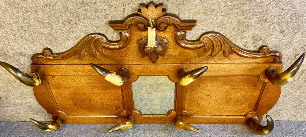 A nineteenth-century wall-mounted carved oak hall stand featuring eight horn hooks, a small central mirror, and scrollwork carving. View VII