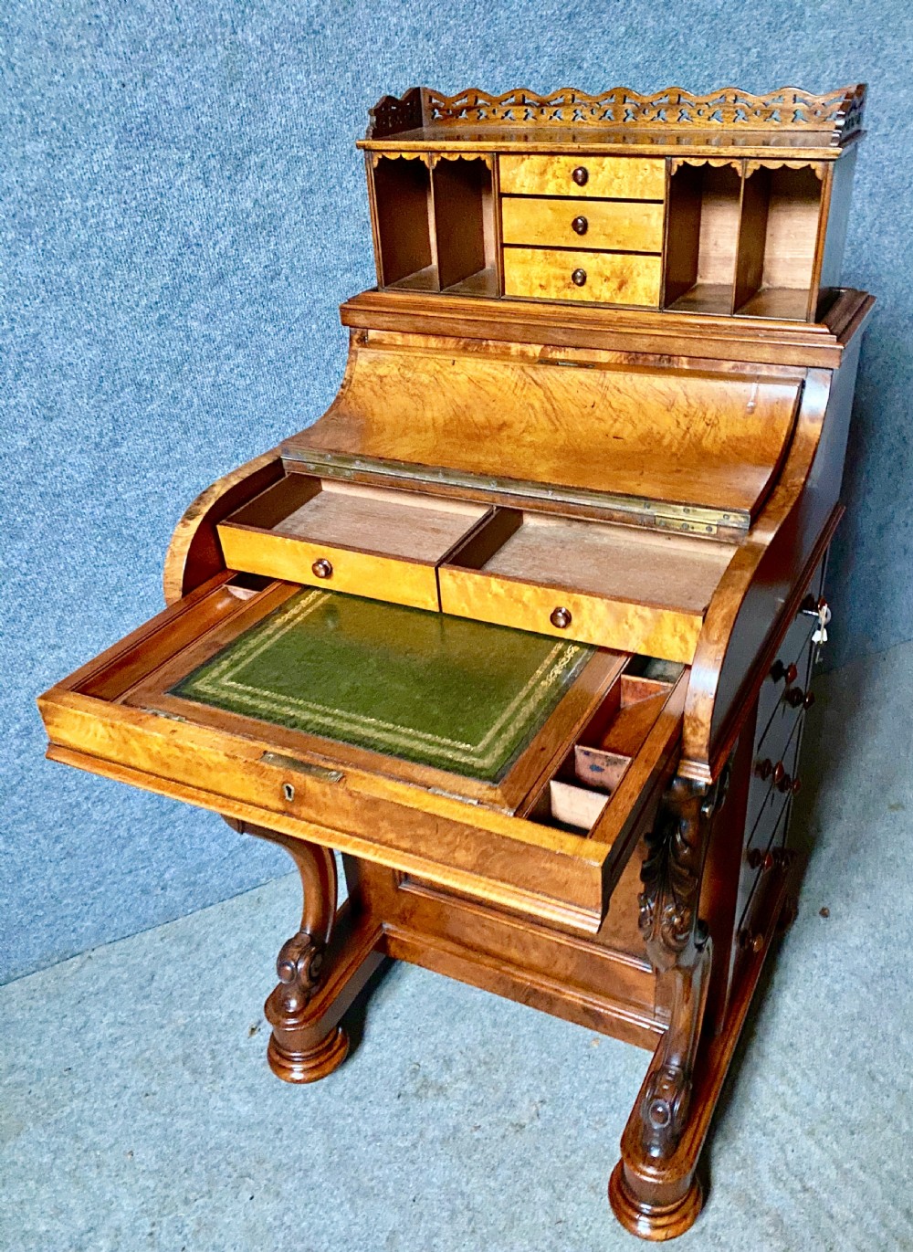 A Victorian burr walnut Davenport desk featuring an elevated pop-up stationery gallery, sloping writing slope with green leather inset, and carved front scroll legs.