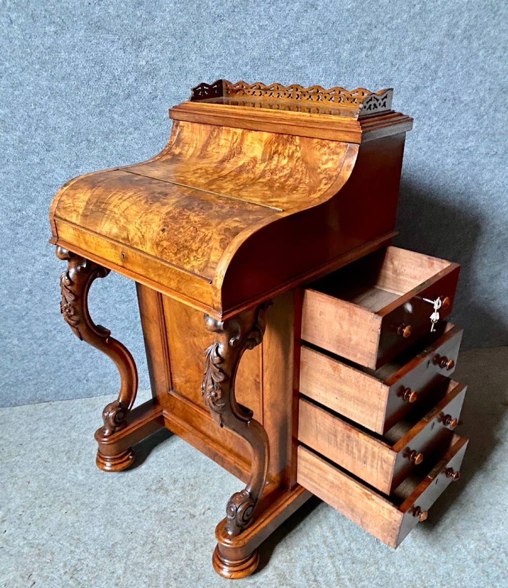 A Victorian burr walnut Davenport desk featuring an elevated pop-up stationery gallery, sloping writing slope with green leather inset, and carved front scroll legs. View VII