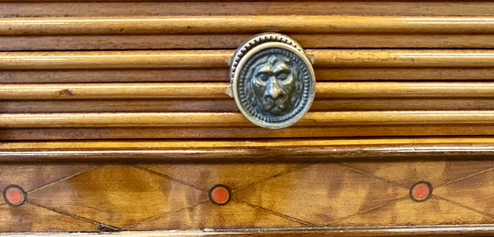 A George III satinwood cylinder desk featuring an arched cresting, a tambour roll top, two frieze drawers, and lower cupboard doors with oval inlay panels. View VI
