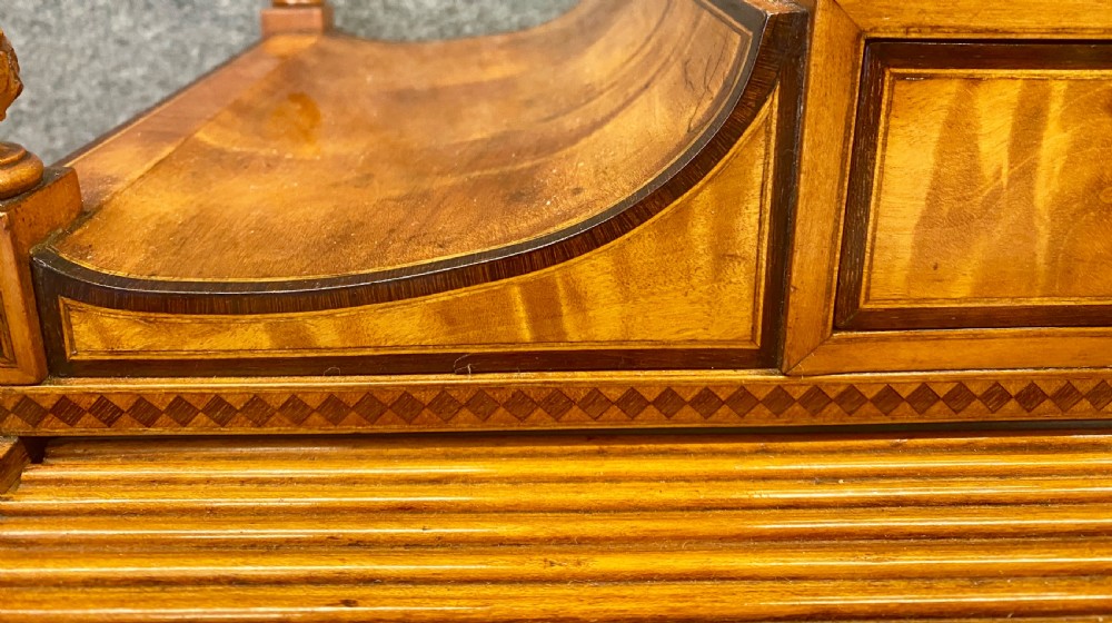 A George III satinwood cylinder desk featuring an arched cresting, a tambour roll top, two frieze drawers, and lower cupboard doors with oval inlay panels. View VIII