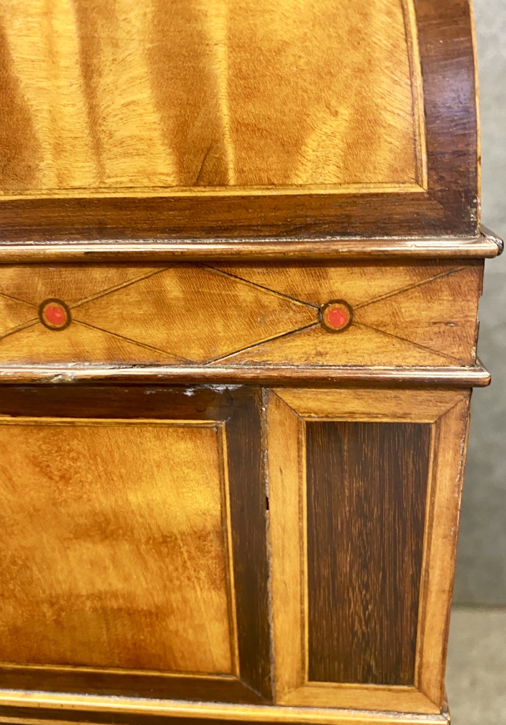 A George III satinwood cylinder desk featuring an arched cresting, a tambour roll top, two frieze drawers, and lower cupboard doors with oval inlay panels. View XIII