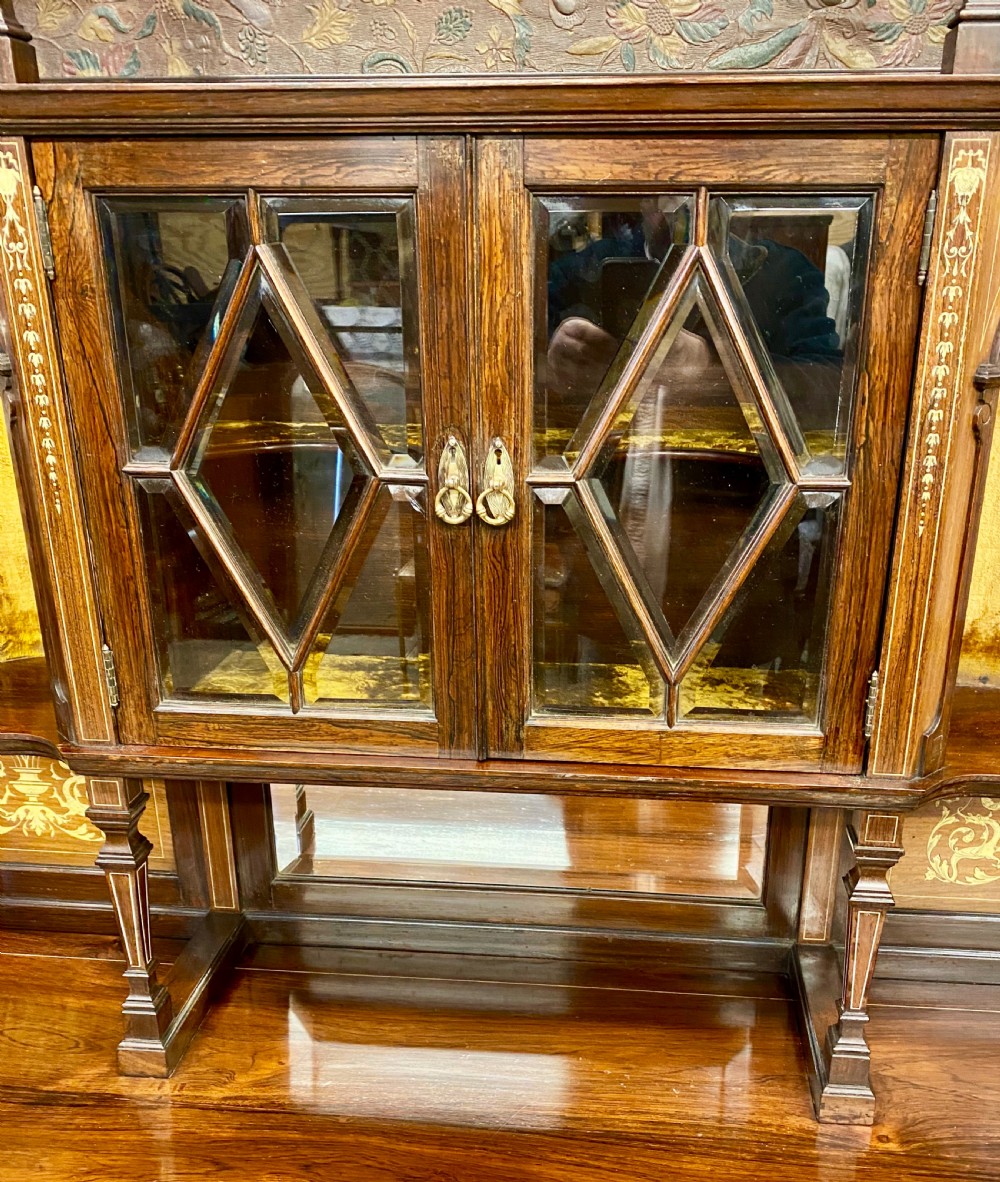 An Aesthetic Movement dark wood side cabinet featuring detailed marquetry inlays, an elevated superstructure with a central glazed cabinet, open niches, a mirror, a single drawer, and lower shelf spaces. View VI